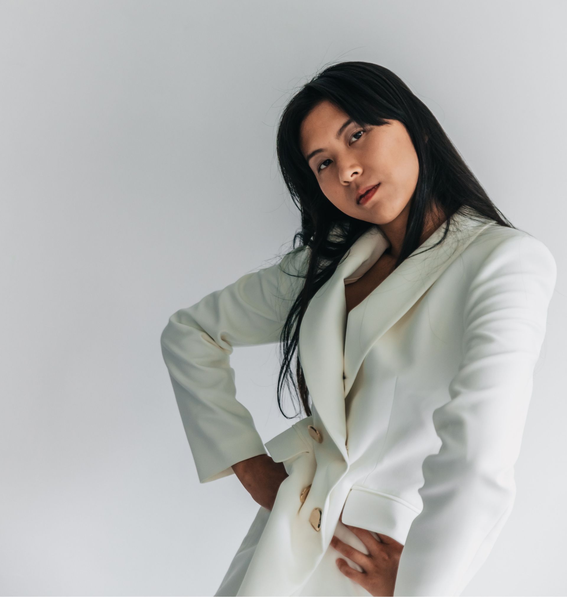 A woman in a white coat is standing with her hands on her hips