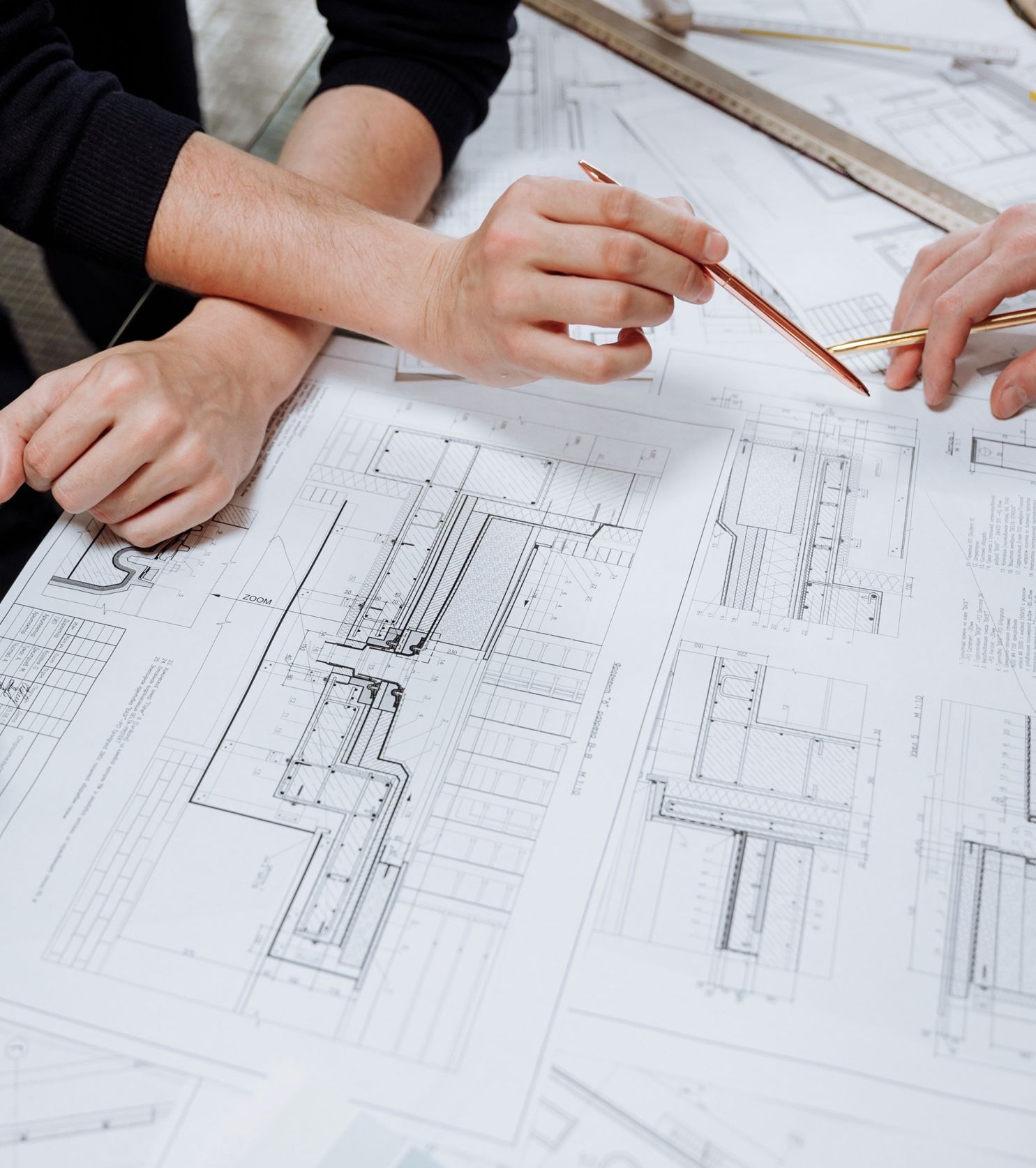 Two people reviewing architectural blueprints, pointing with pencils.