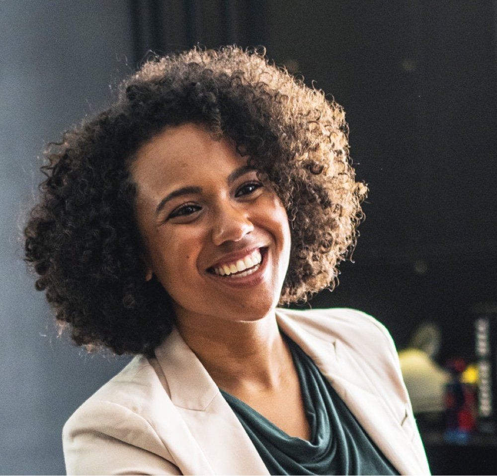 a woman with curly hair is smiling for the camera