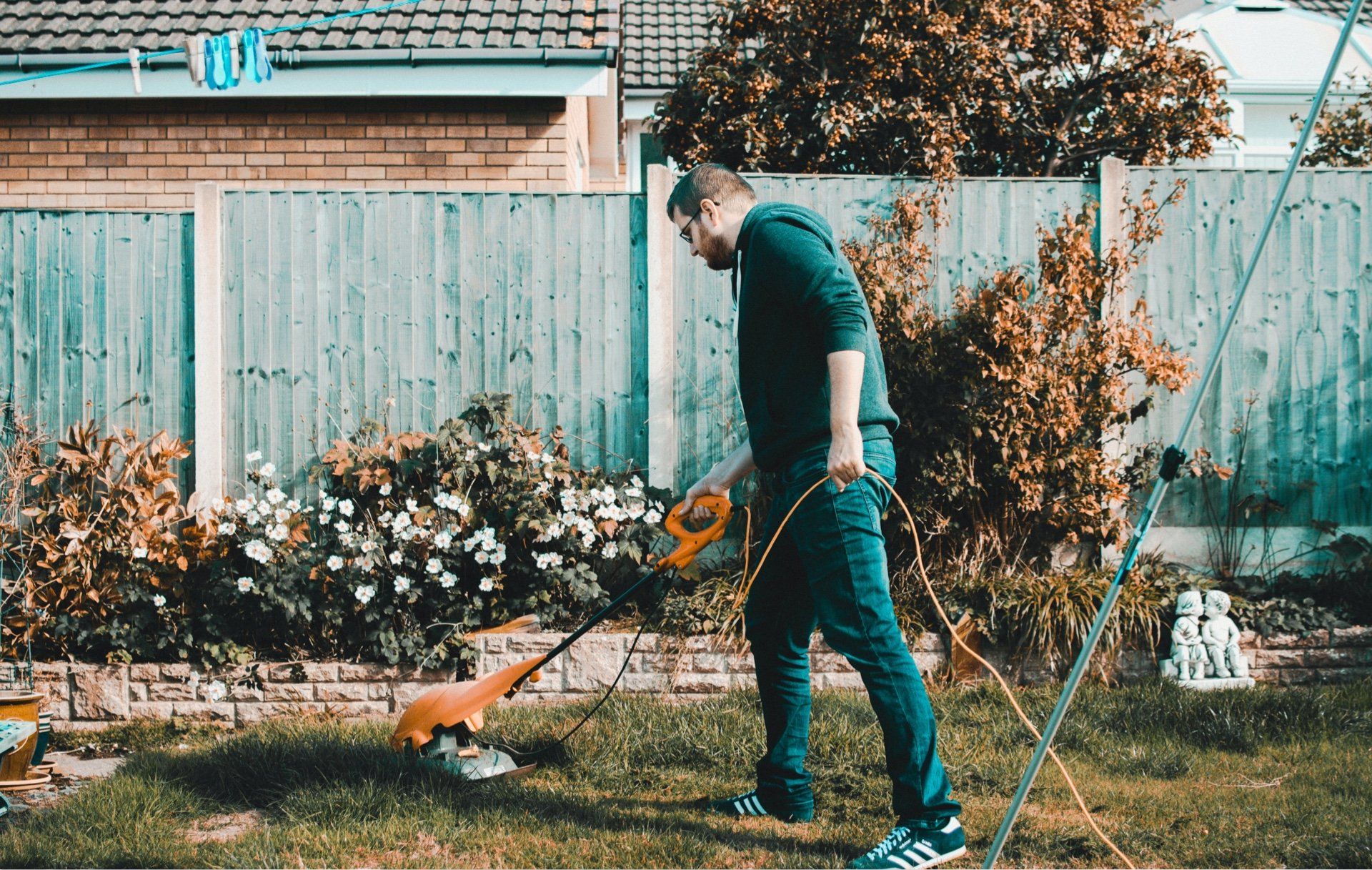 Een man gebruikt een grasmaaier om het gras in zijn achtertuin te maaien.