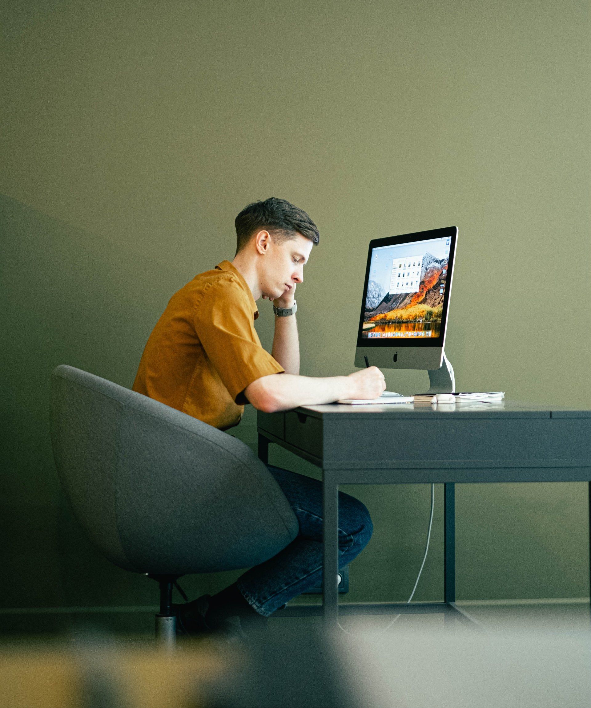 Een man zit aan een bureau en werkt op een computer