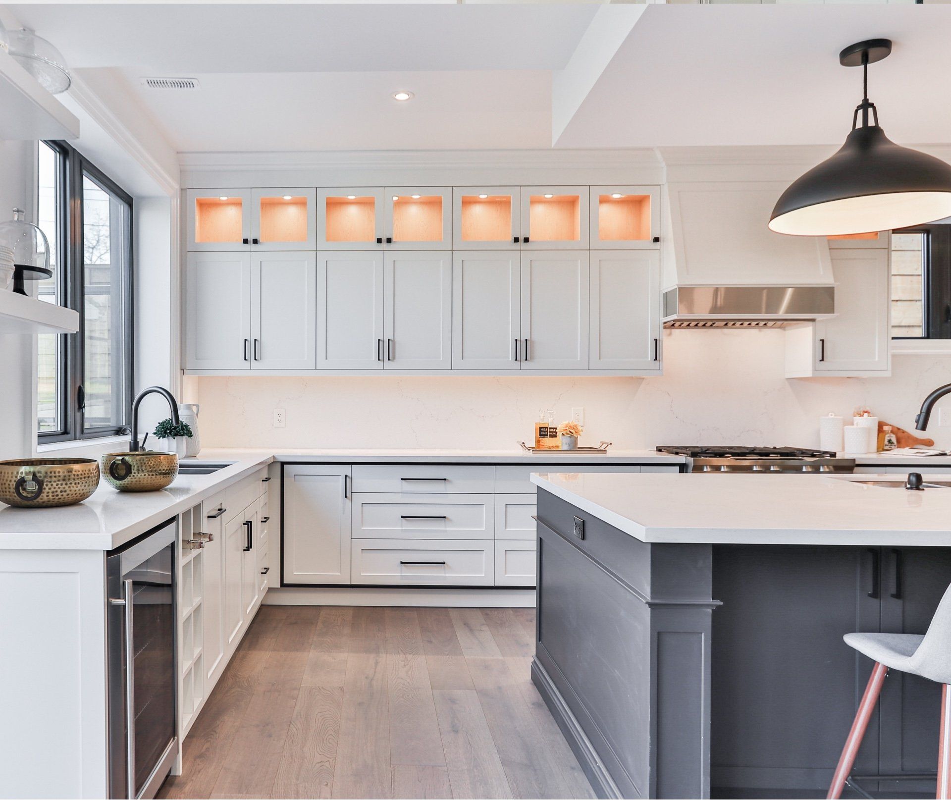 A kitchen with white cabinets , stainless steel appliances , and a large island.