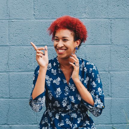 A woman with red hair is smiling and pointing at something