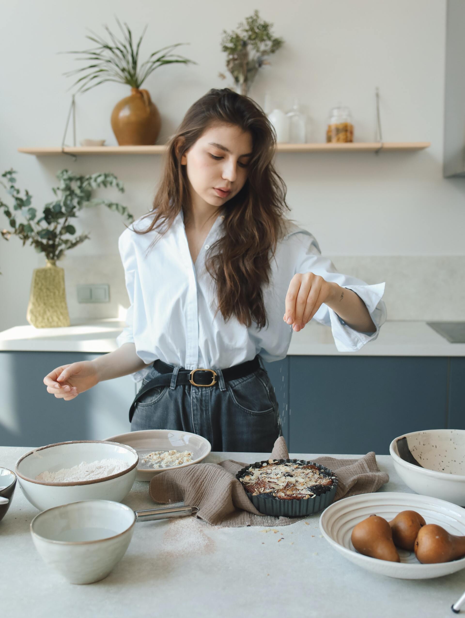 A woman is standing at a table in a kitchen preparing food.