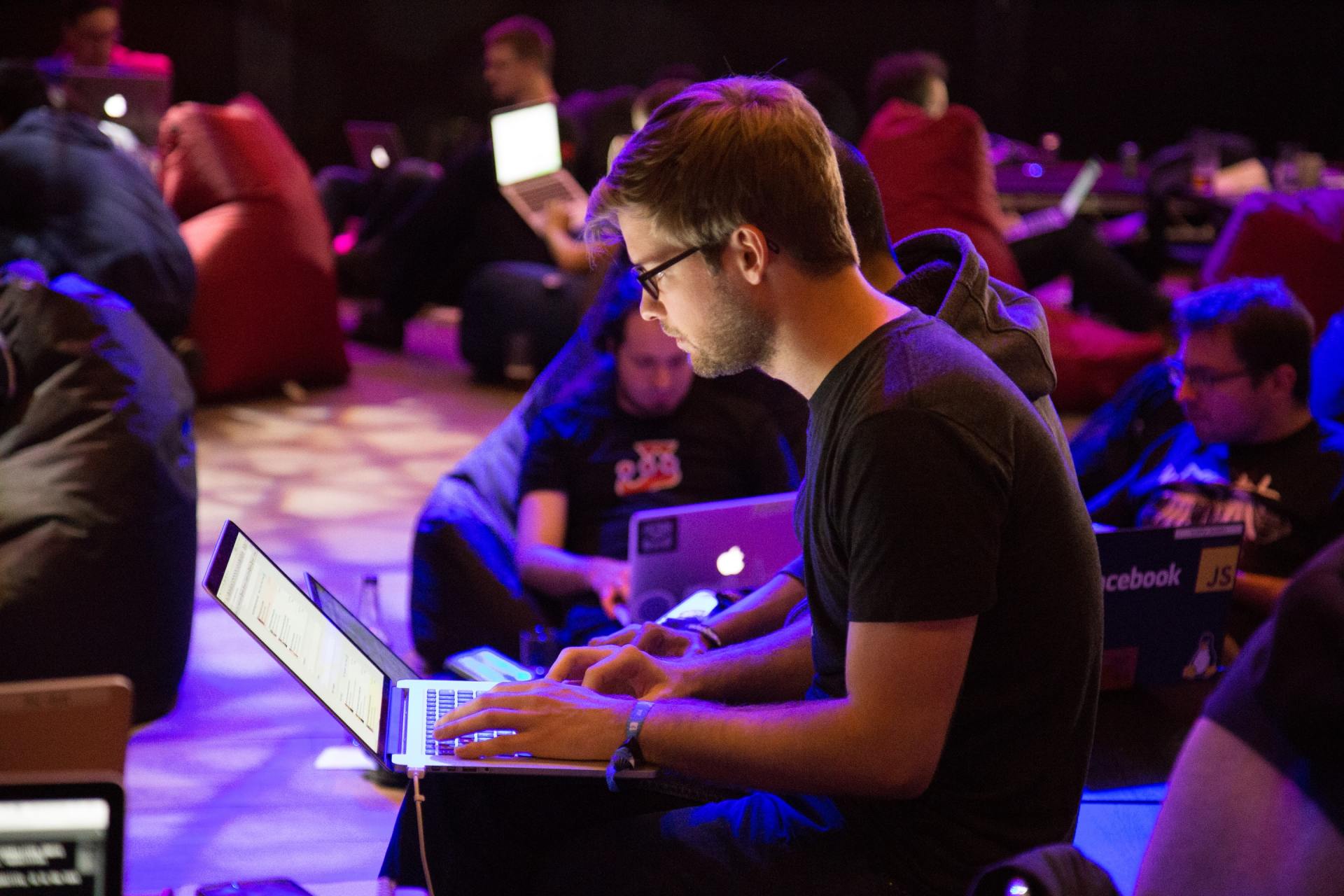A man is sitting on the floor using a laptop computer.