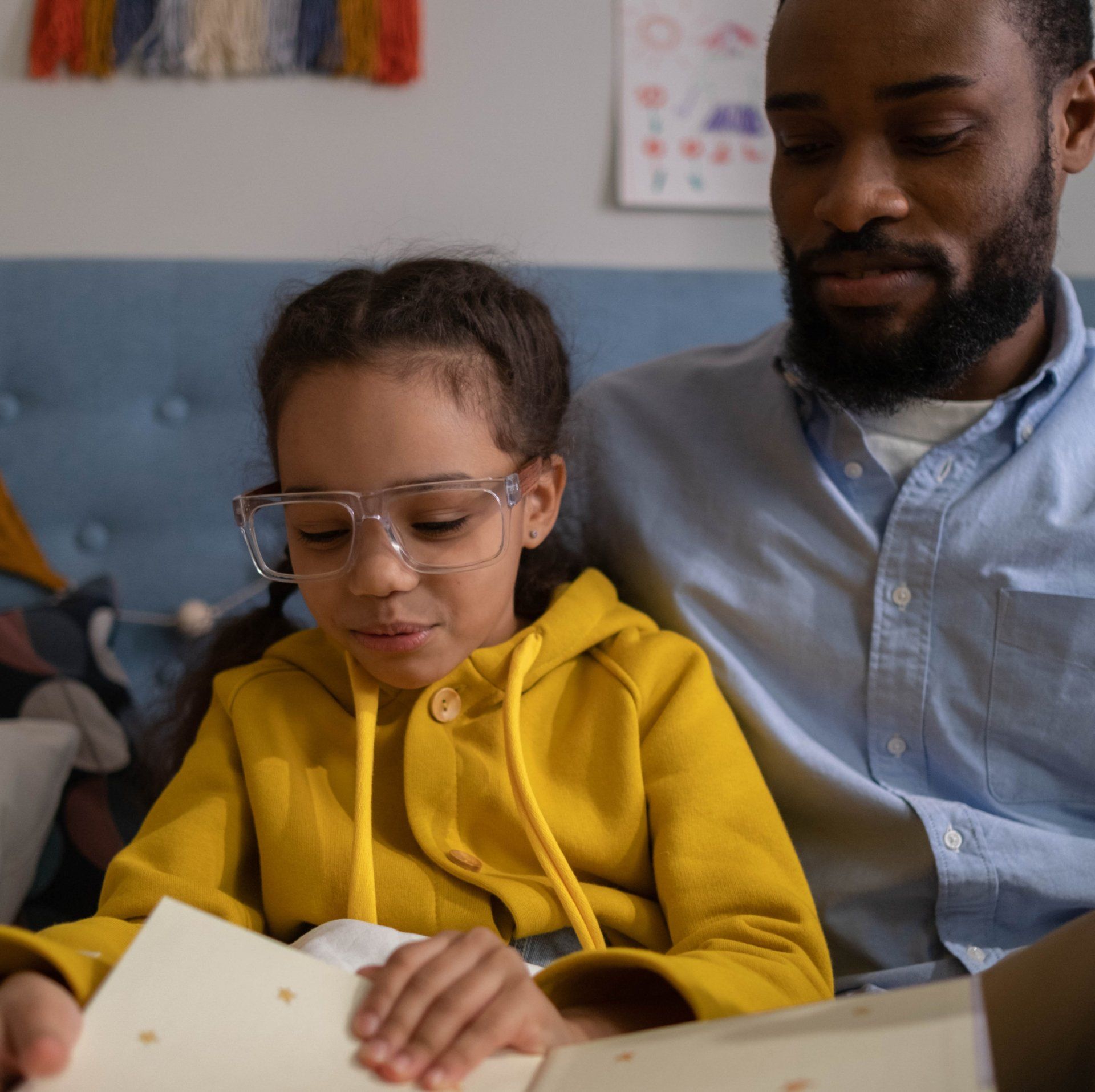 A man and a little girl are reading a book together.