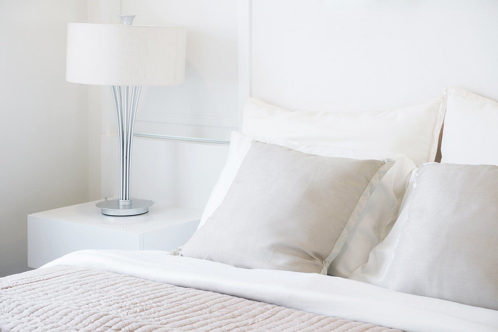 Há uma luminária na mesa de cabeceira ao lado da cama.