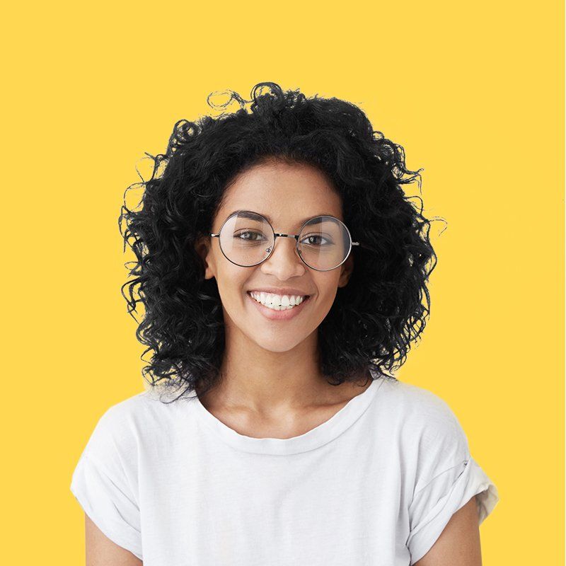 A woman wearing glasses and a white shirt is smiling on a yellow background.