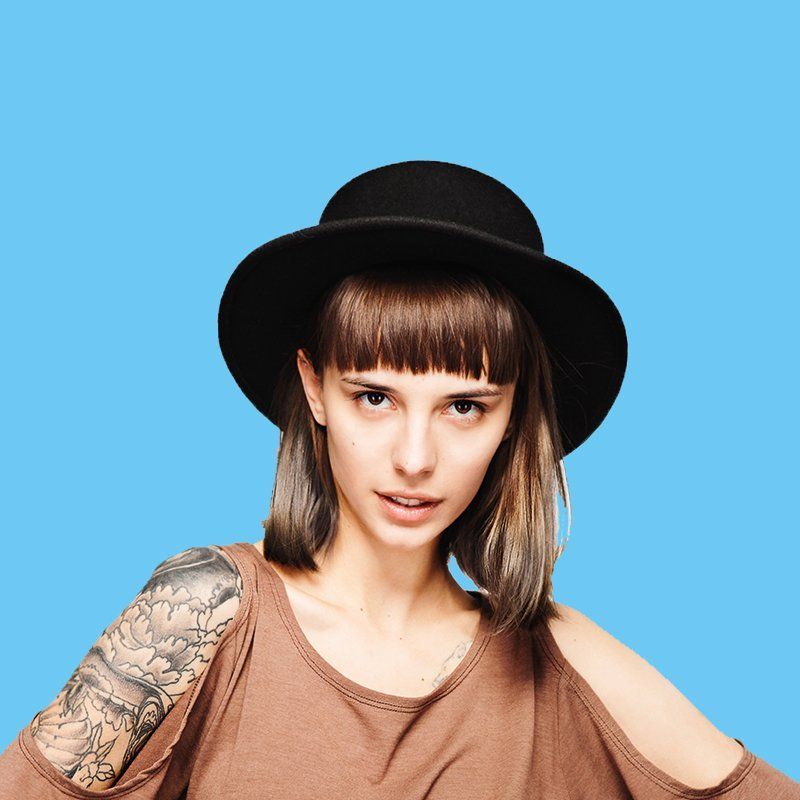A woman with a tattoo on her arm is wearing a hat.