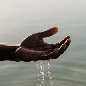 A person 's hand is reaching out towards the water