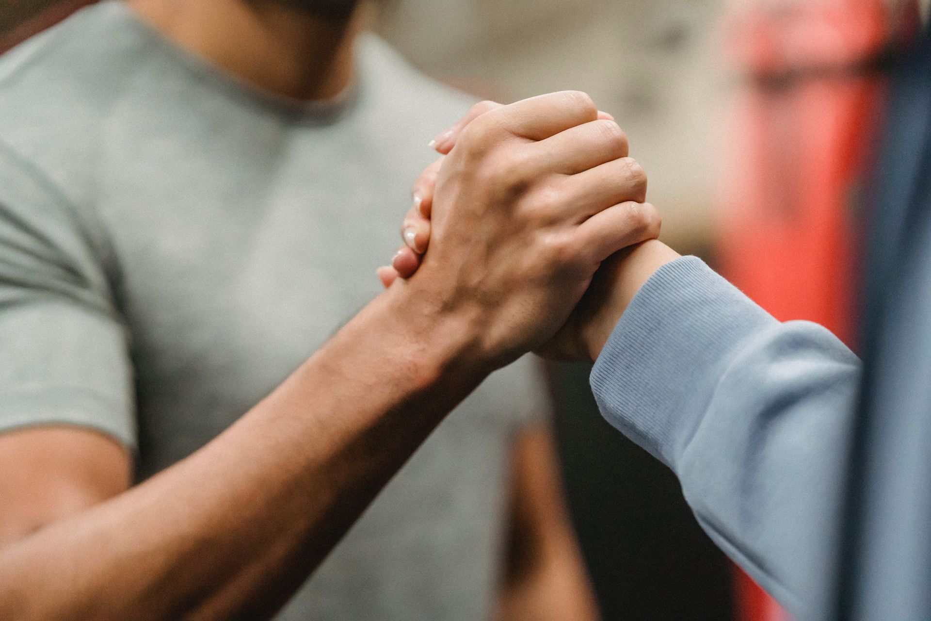 A man and a woman are shaking hands in a gym.