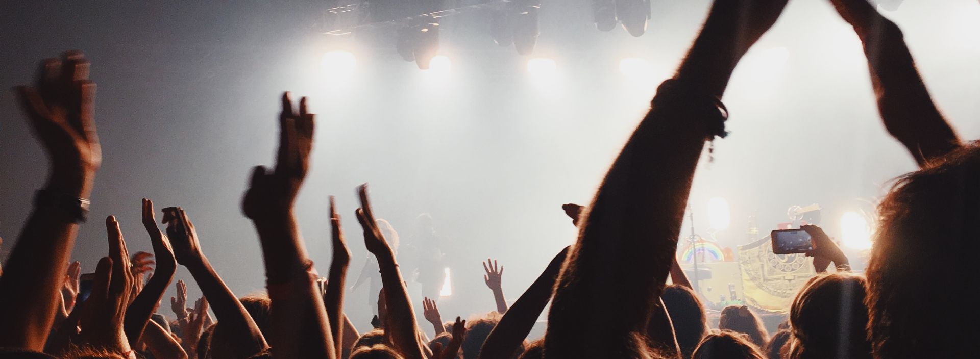 A crowd of people are raising their hands in the air at a concert.