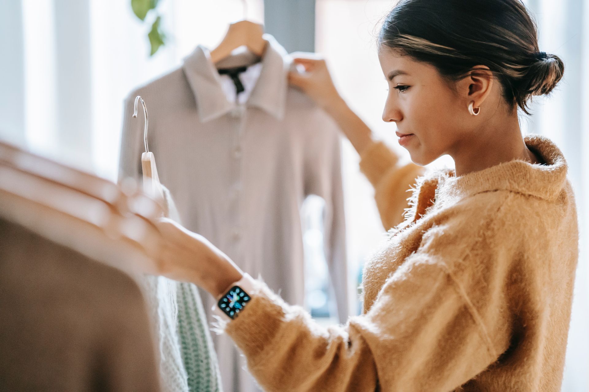 A woman is looking at a shirt on a hanger in a store.