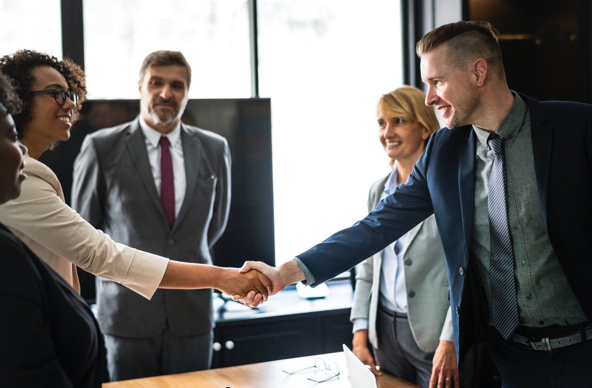 Business people shaking hands in a meeting, smiling.