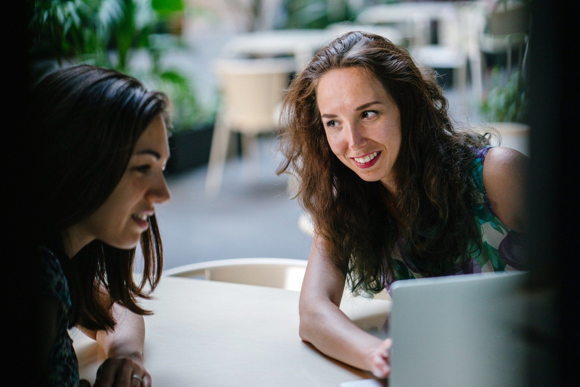 two women sit at a table looking at a laptop learning SEO
