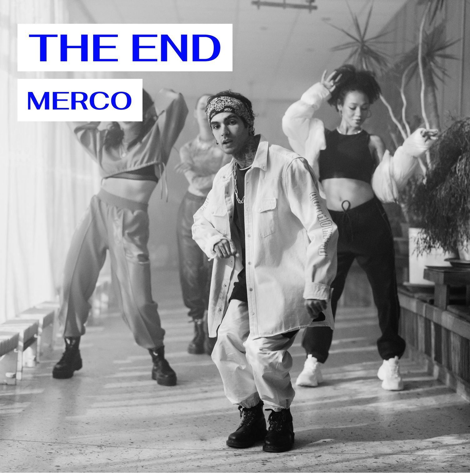 A black and white photo of a group of people dancing under the title the end merco