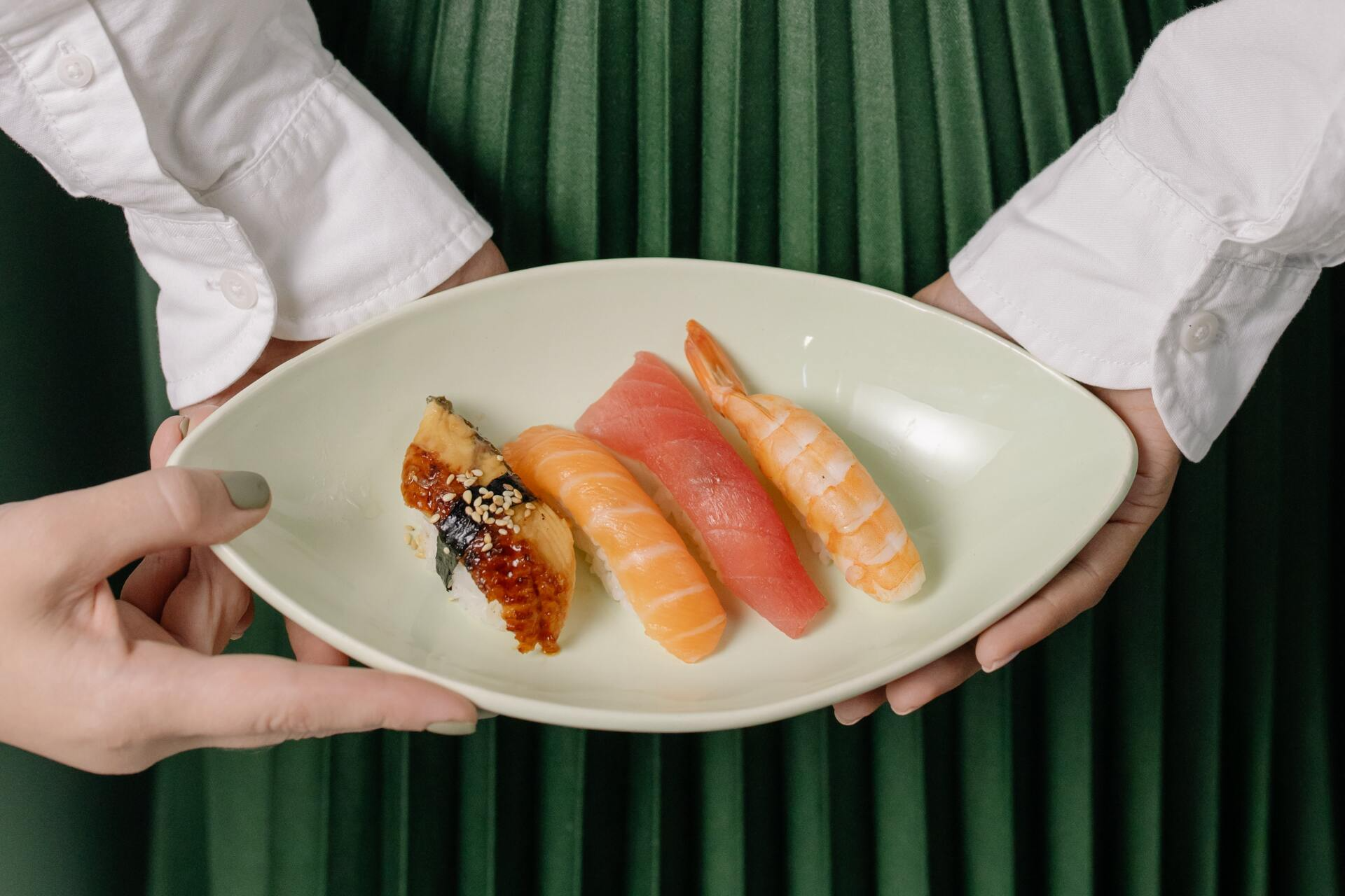 A person is holding a plate of sushi in their hands.