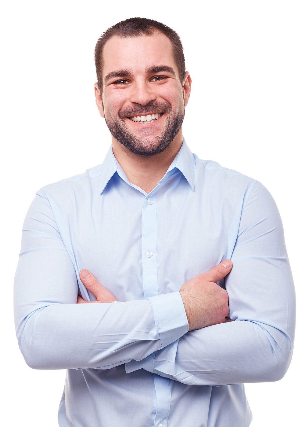 A man in a blue shirt is standing with his arms crossed and smiling.