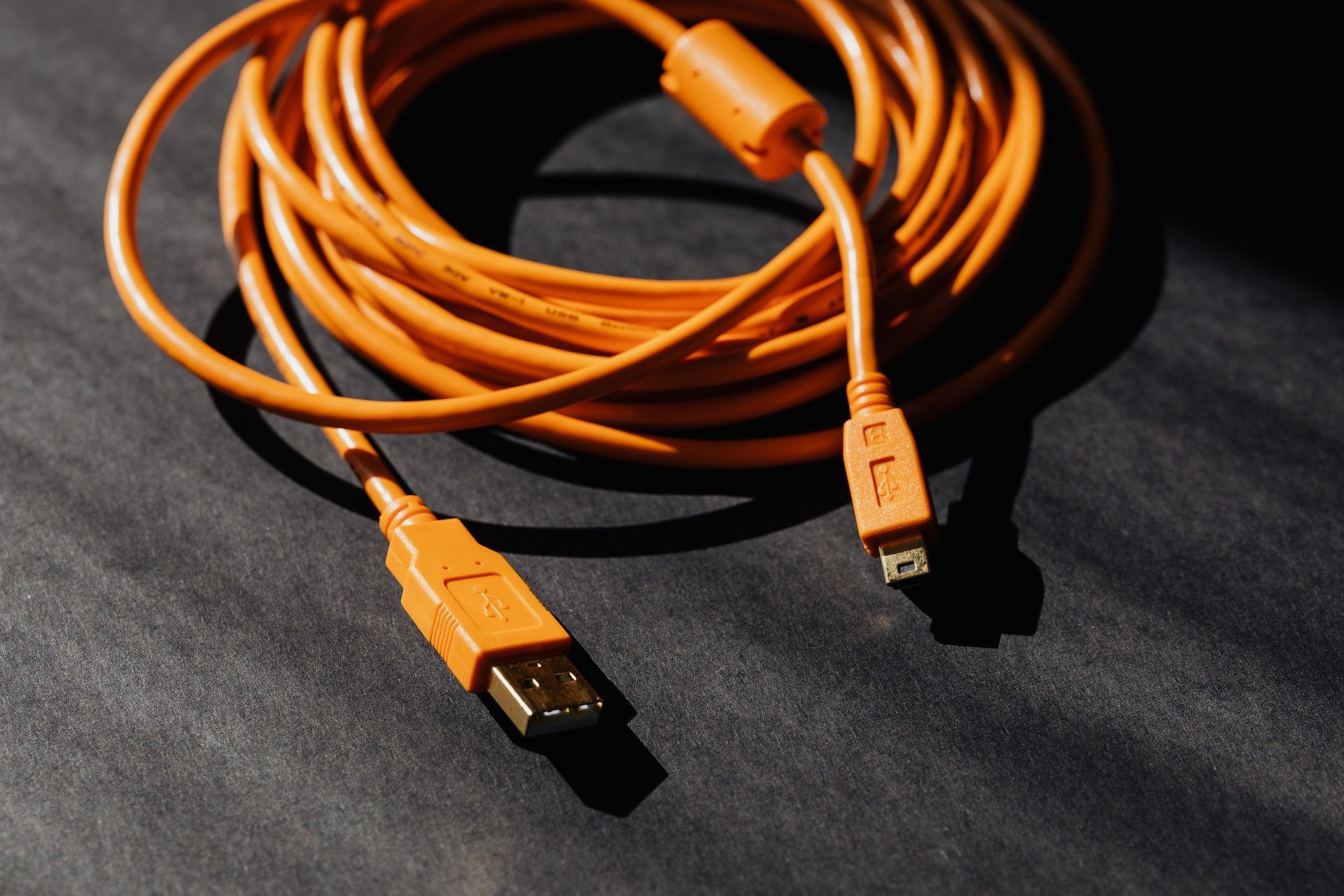 An orange usb cable is laying on a black surface