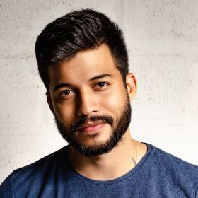 A man with a beard is wearing a blue shirt and looking at the camera.