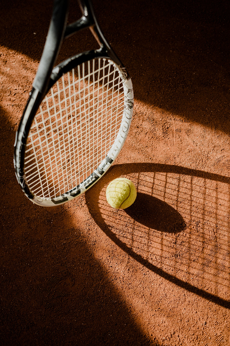 A tennis racket and ball are on a tennis court.