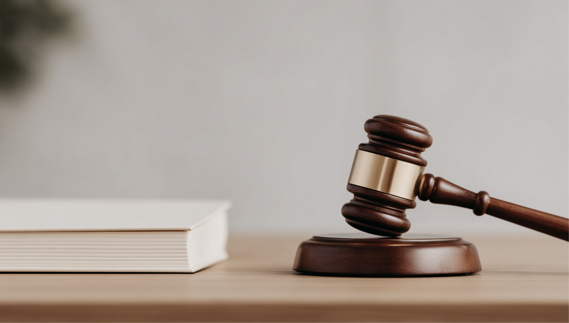 Wooden gavel on a sound block next to a closed book on a table.