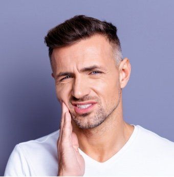 Man with a grimace, holding his jaw, showing signs of tooth pain.