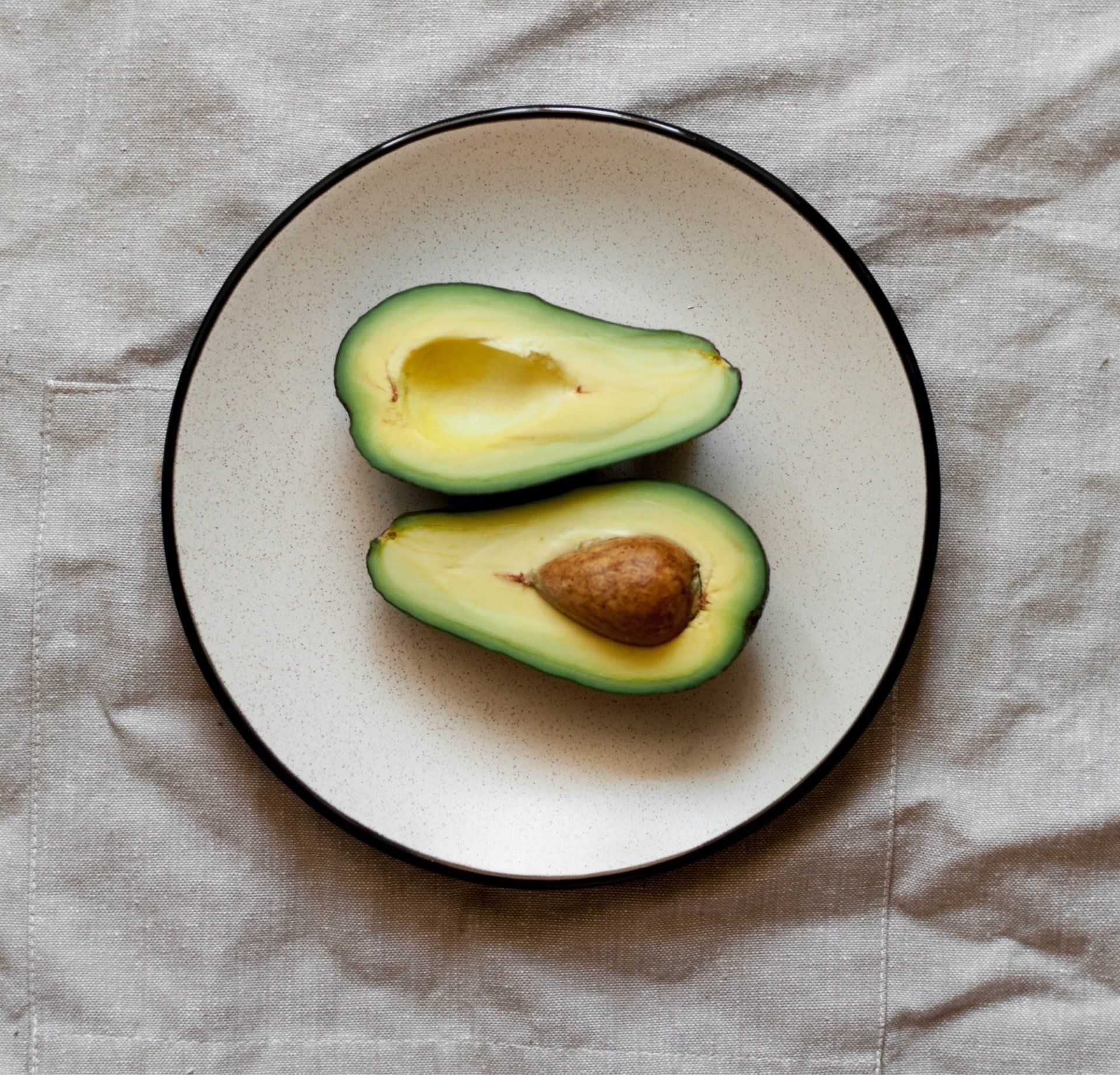 Dos aguacates cortados por la mitad en un plato blanco