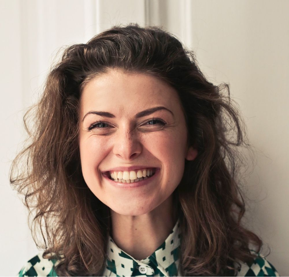 A woman wearing a green and white shirt is smiling
