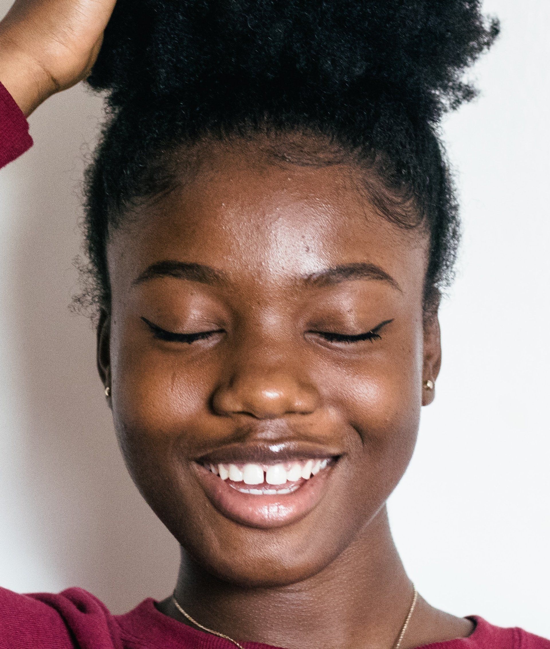 A woman is smiling with her eyes closed and her hair in a bun.