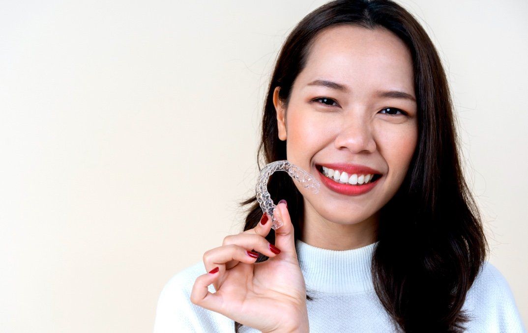 A woman is holding a clear brace in her hand and smiling.