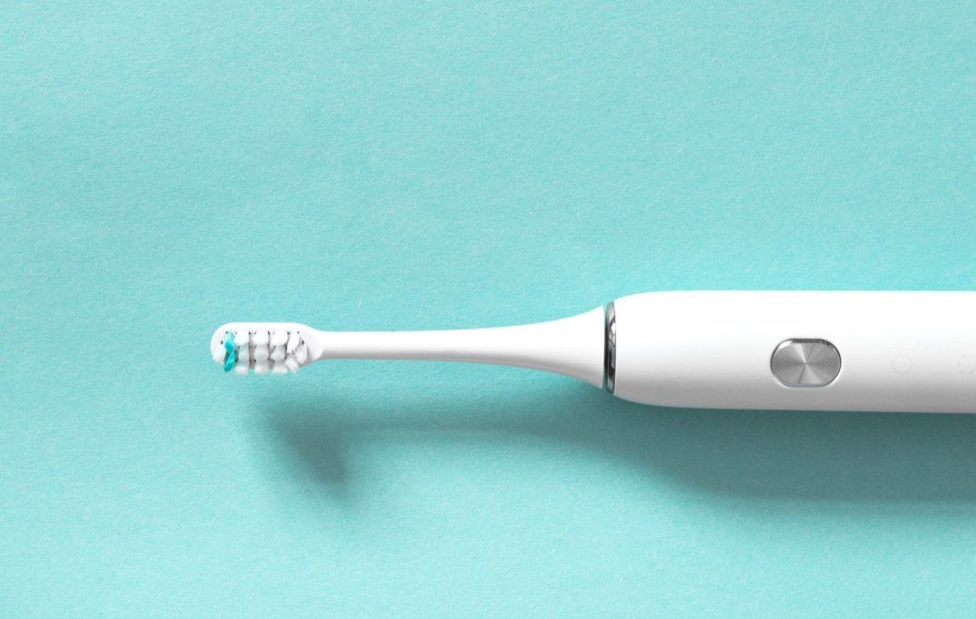 An electric toothbrush is sitting on a blue surface.