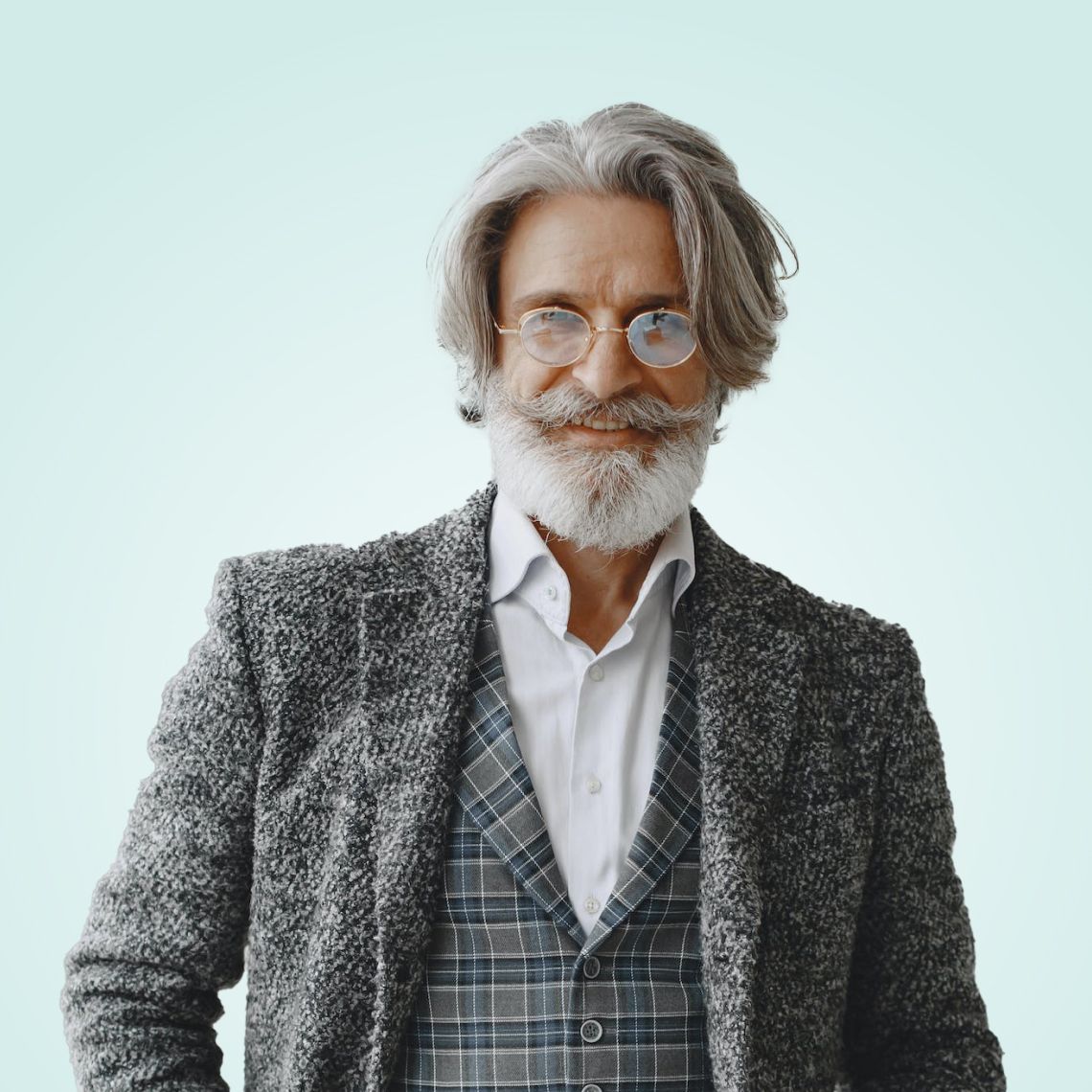 Smiling man with gray hair and beard in a tweed jacket against a light background