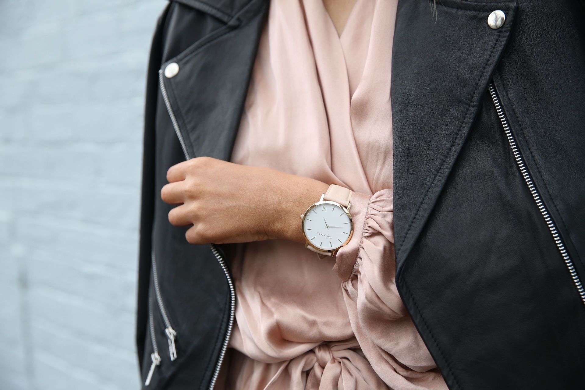 A woman wearing a leather jacket and a watch on her wrist.