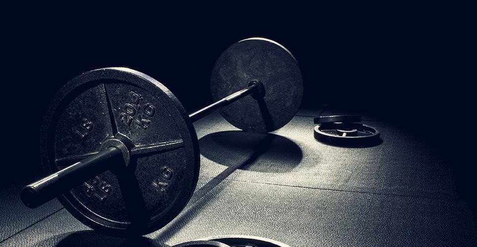 A black and white photo of a barbell and weights on the floor.
