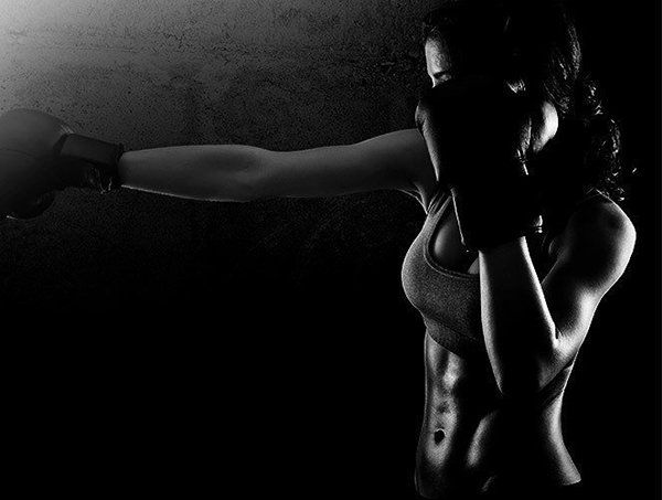 A black and white photo of a woman wearing boxing gloves.