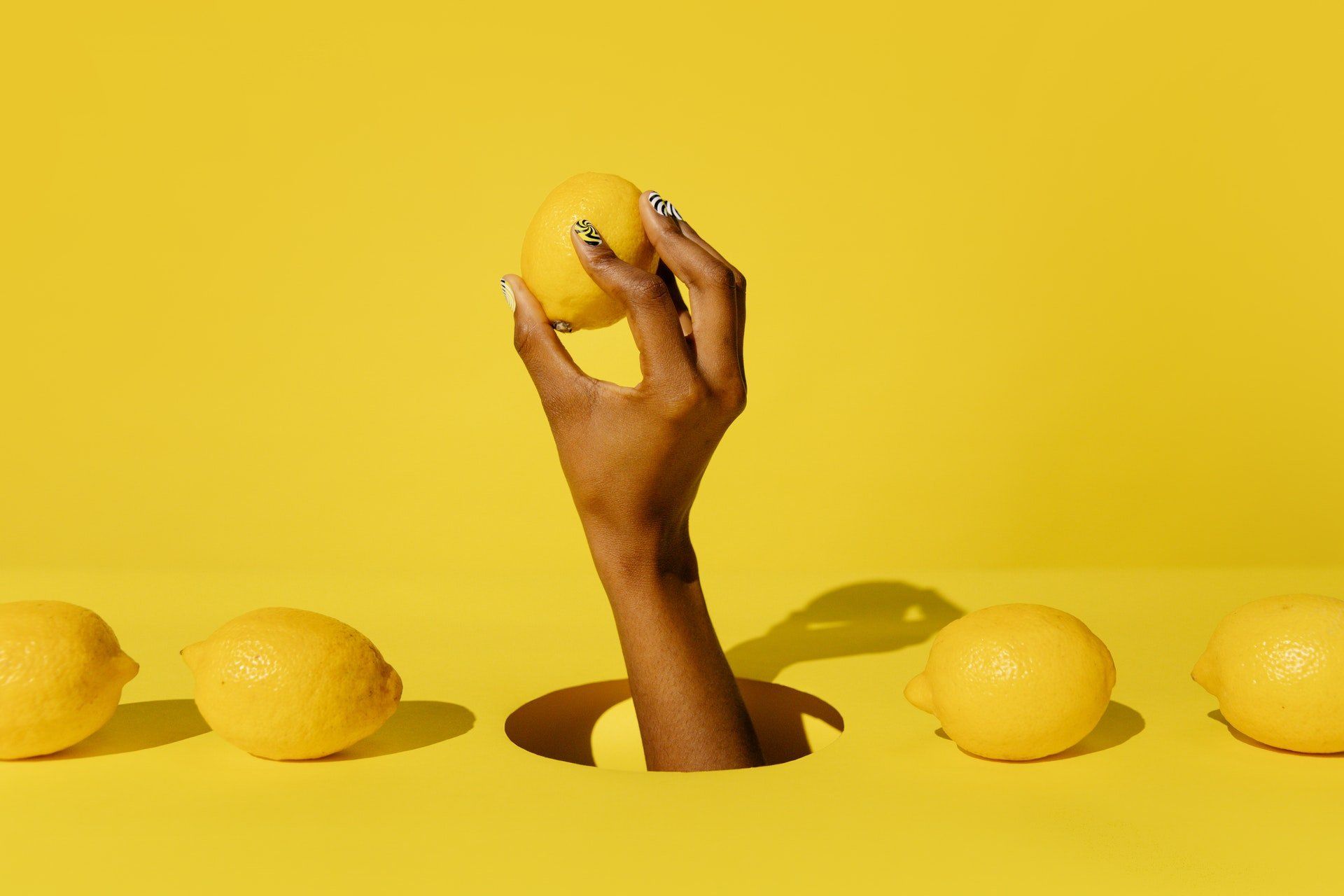 La mano de una mujer sobresale de un agujero sosteniendo un limón.