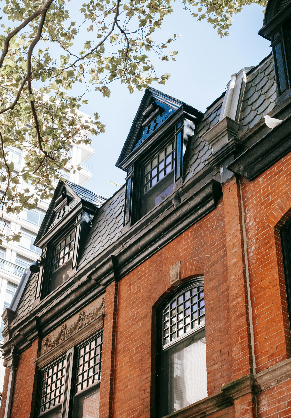A brick building with a black roof and a lot of windows.