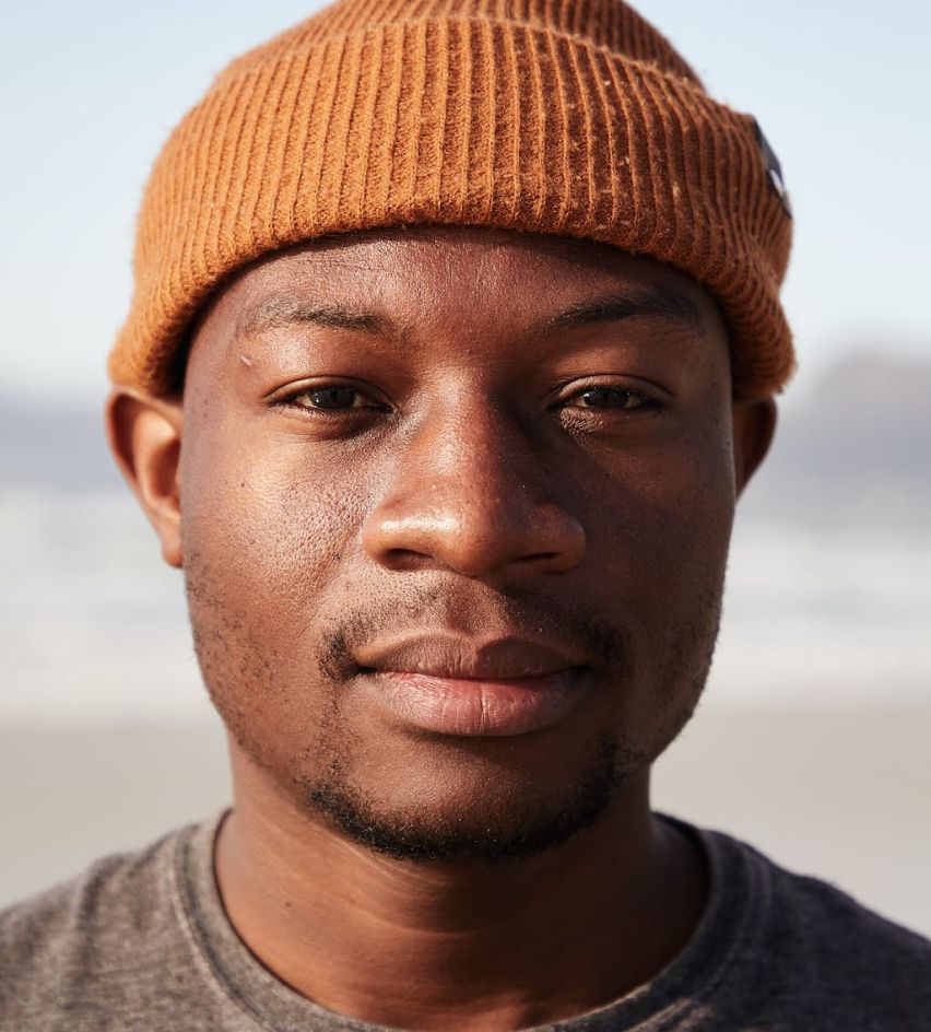 A close up of a man wearing a beanie and a grey shirt