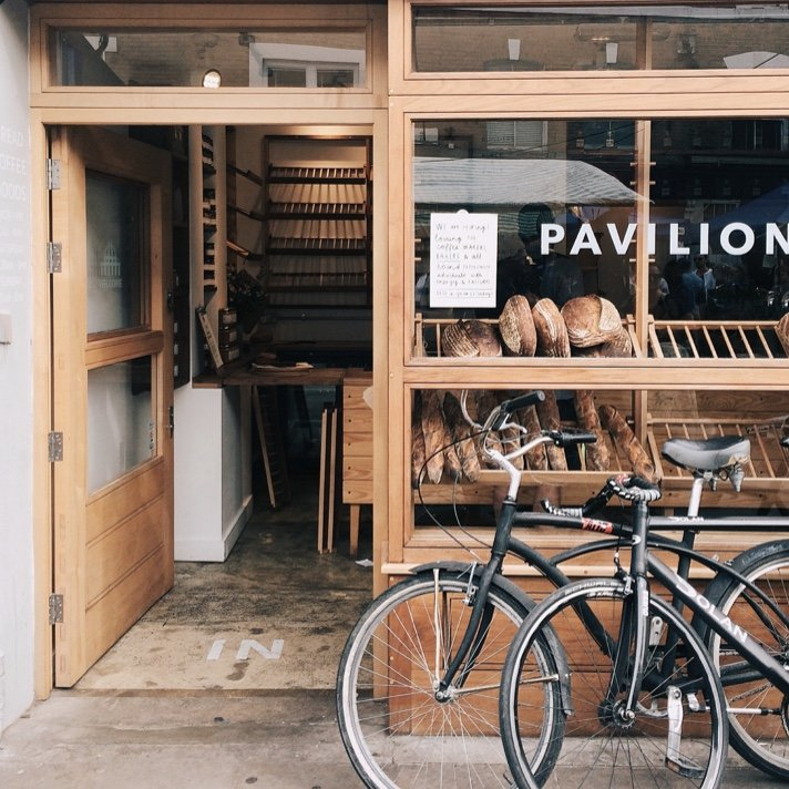 Two bicycles are parked in front of a pavilion bakery