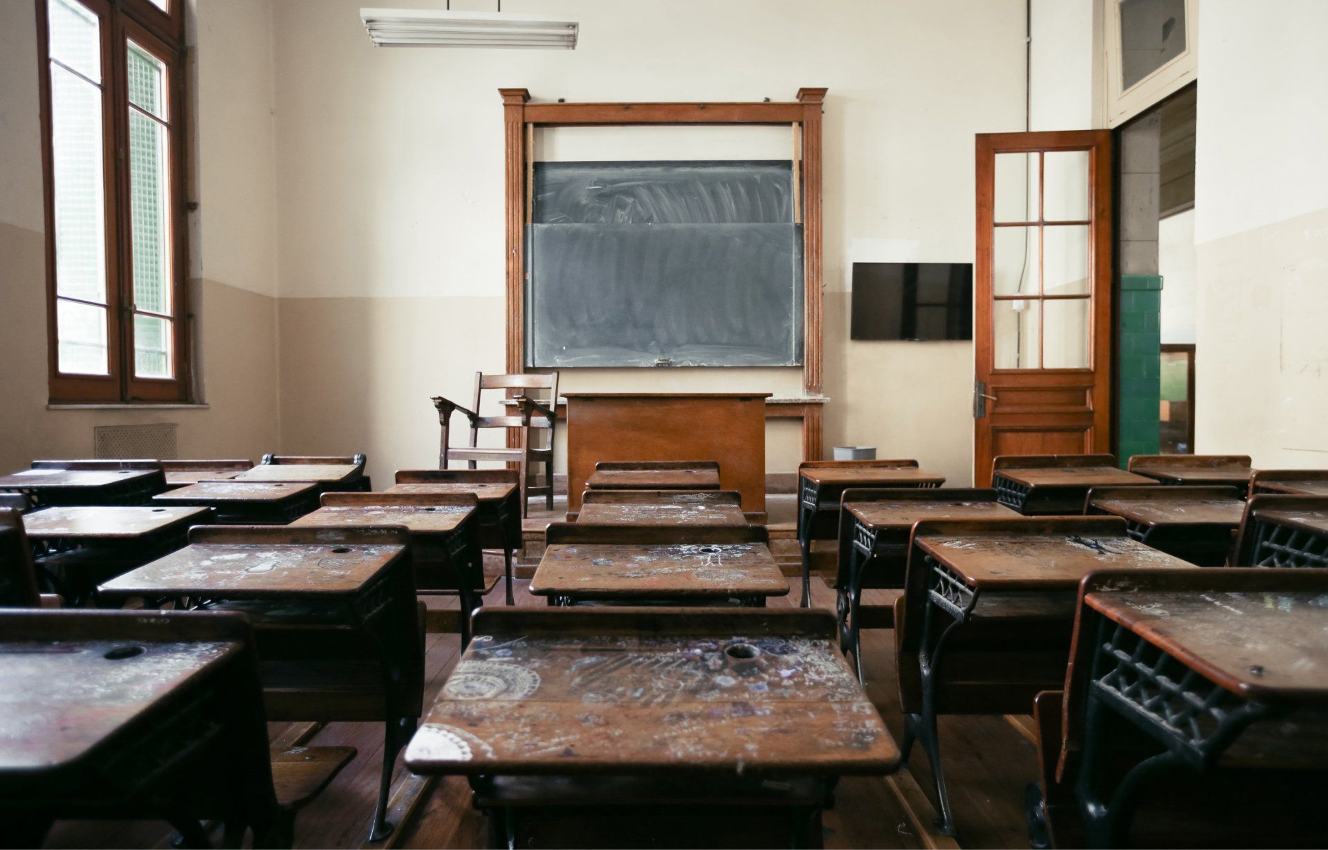 An empty classroom with wooden desks and a blackboard.
