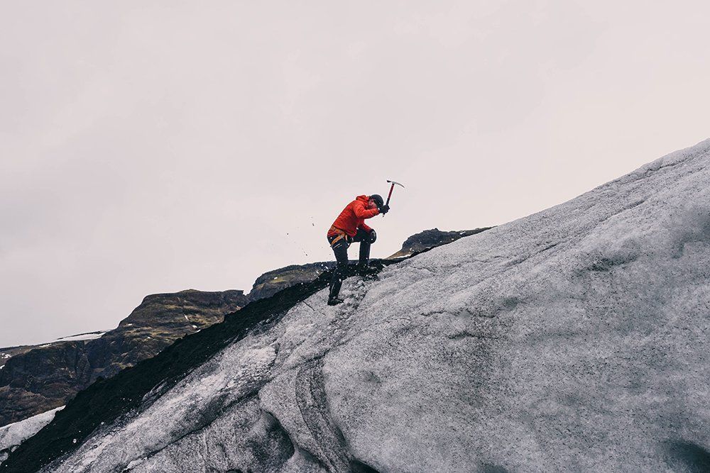 Ein Mann in einer roten Jacke besteigt einen schneebedeckten Berg.