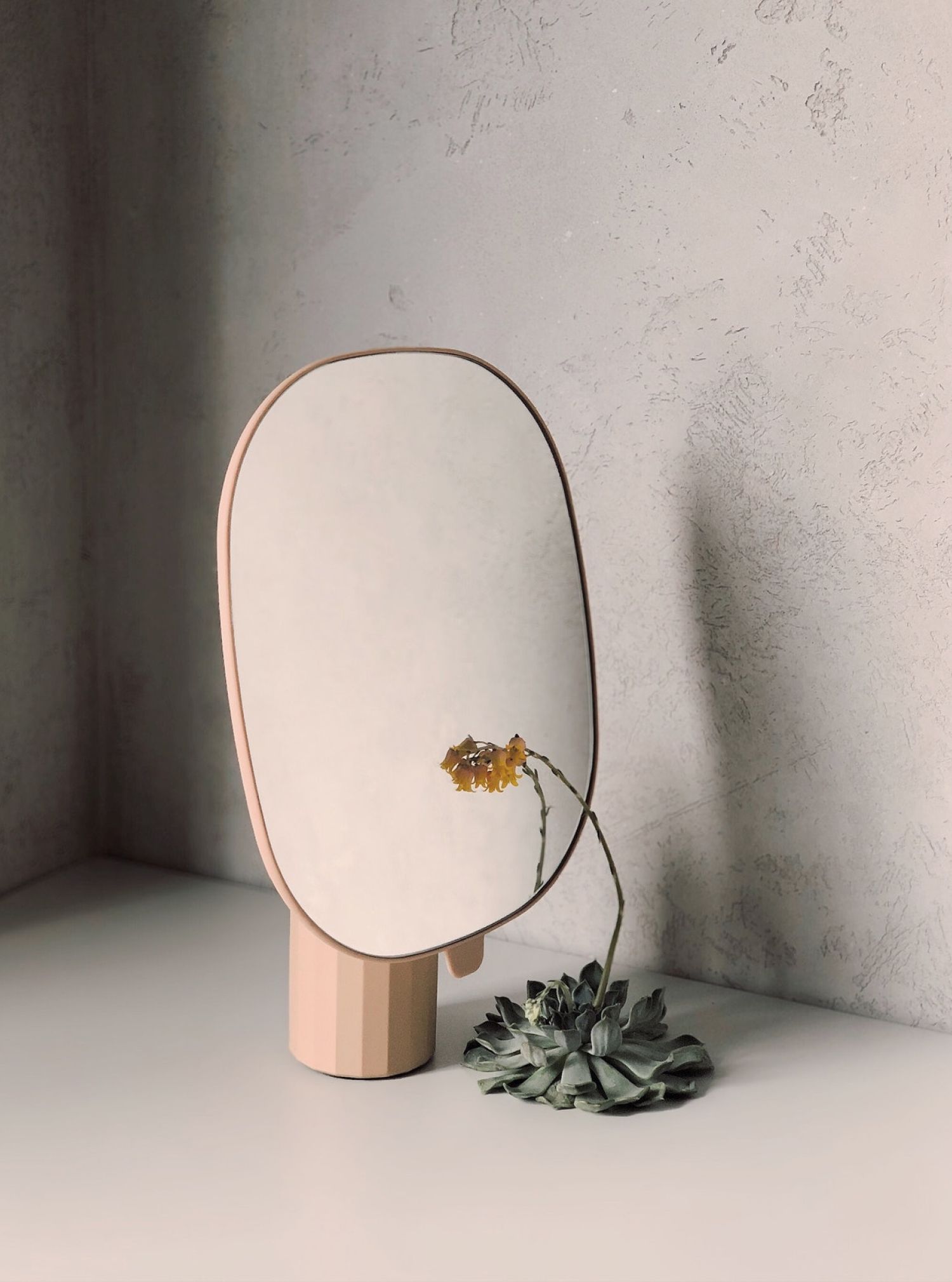 A mirror with a flower in it is sitting on a table.