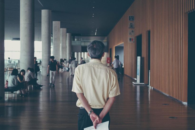 A man is standing in a hallway holding a piece of paper.