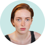 A woman with red hair and freckles is looking at the camera in a circle.