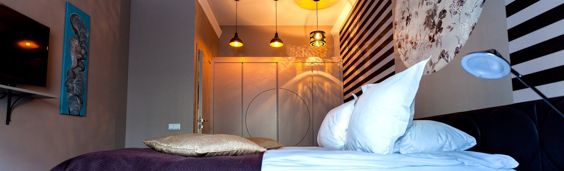 Bedroom with a bed, pillows, TV, and artistic wall decor.