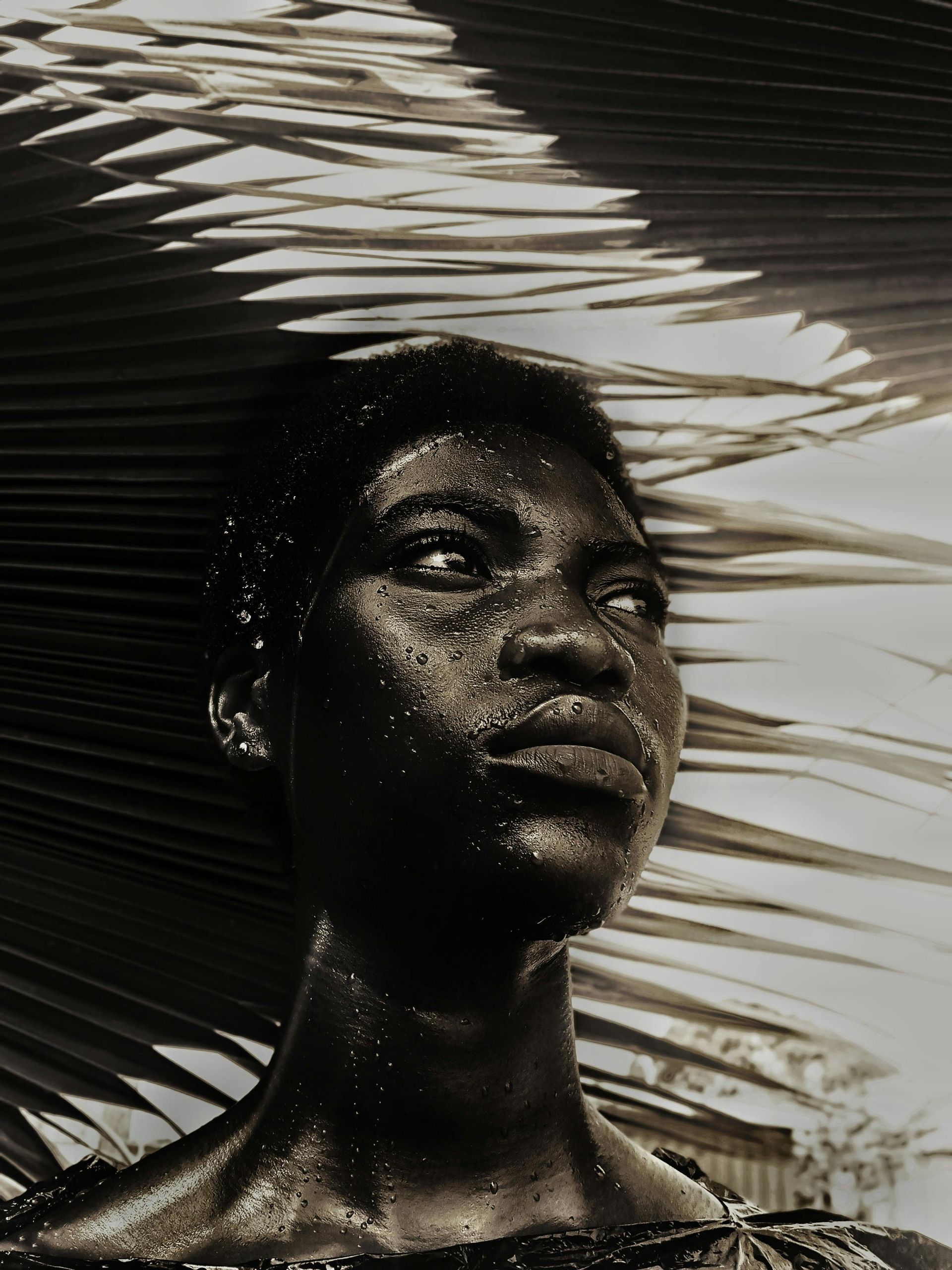 A black and white photo of a woman with palm leaves in the background