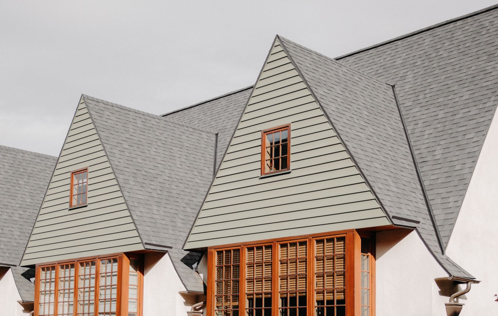 Triangular roofline with dormer windows and large wooden-framed windows.