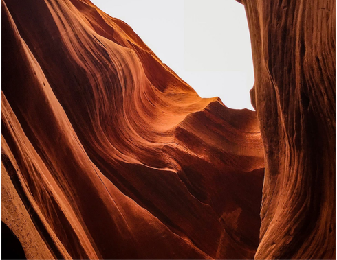 Sunlit red sandstone canyon walls with a narrow opening to the sky