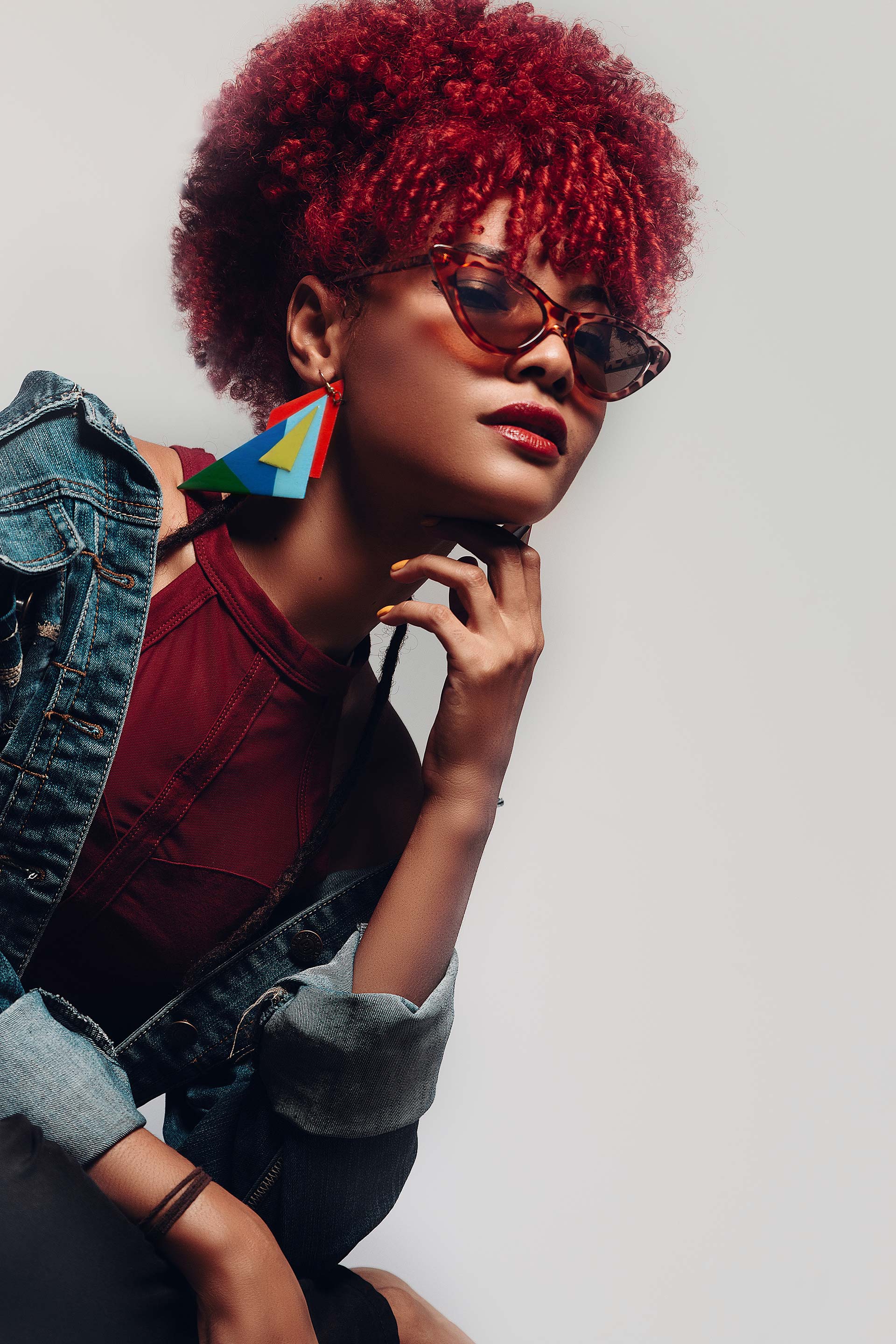 A woman with red hair is wearing sunglasses and earrings.